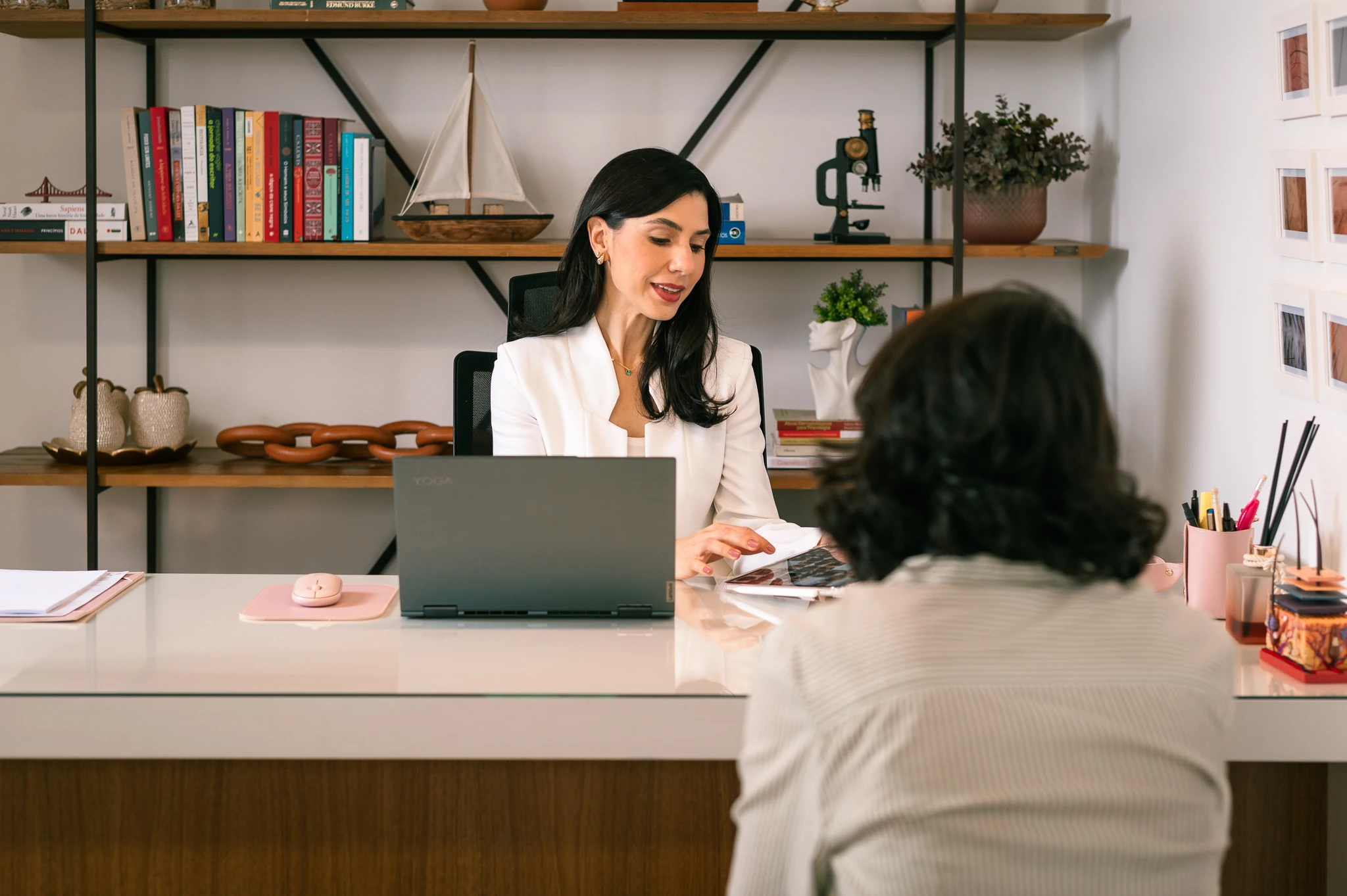 Lívia Viccari em consulta, conversando com uma paciente sobre a avaliação clínica.