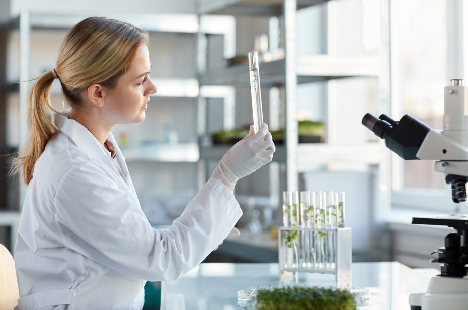 Mercado de trabalho para biomedicina: jovem biomédica segurando um tubo de ensaio com amostras.