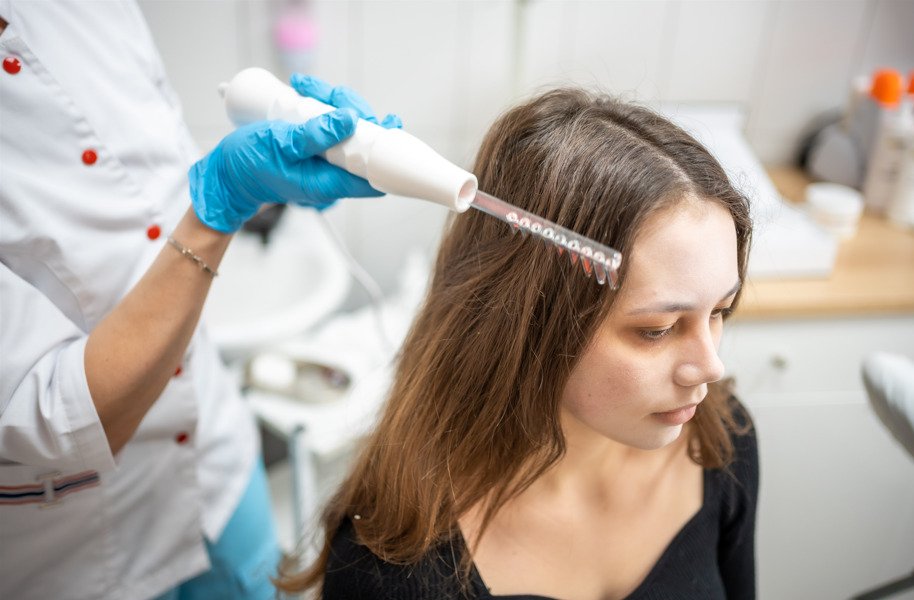 Profissional fazendo tratamento na paciente, fazendo referência a causas da queda de cabelo.