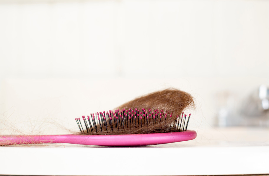 Escova com bastante cabelo, fazendo referência à queda de cabelo pós-parto.