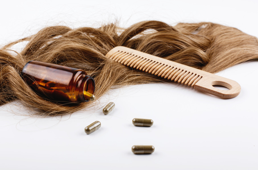 Cabelo, pente e comprimidos fazendo referência à queda de cabelo por deficiência de ferro.