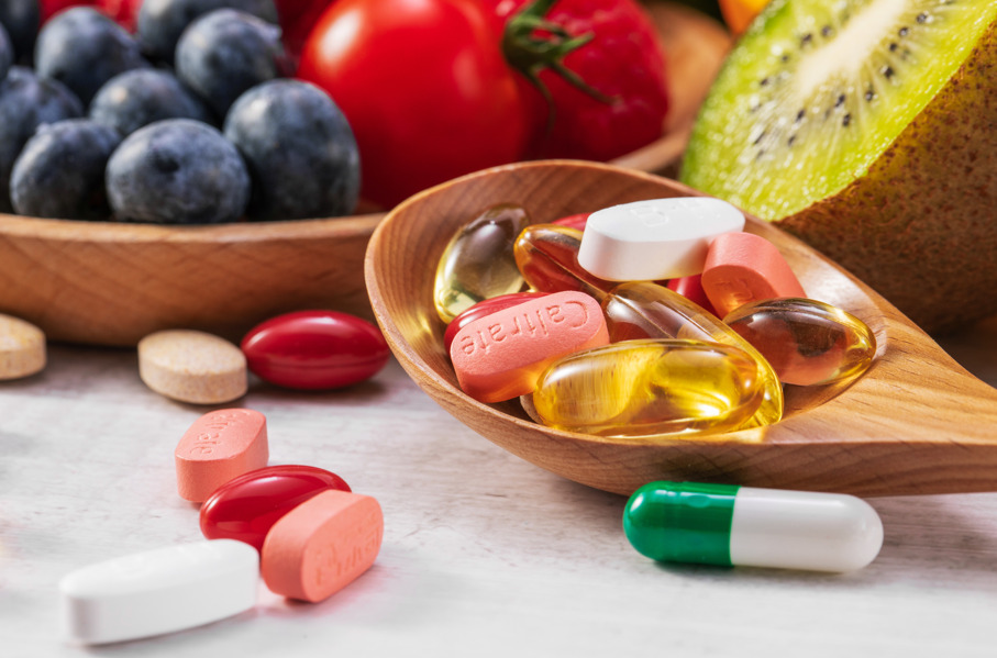 Cápsulas de comprimido e alimentos fazendo referência à queda de cabelo por deficiência de ferro.