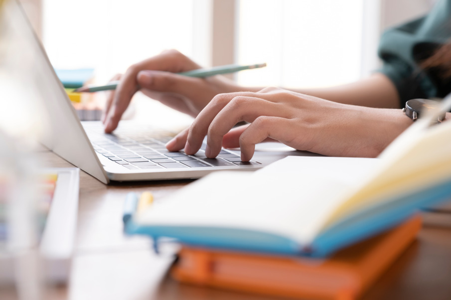 Mãos sobre o laptop fazendo referência a como aprender a tratar queda de cabelo por deficiência de ferro.