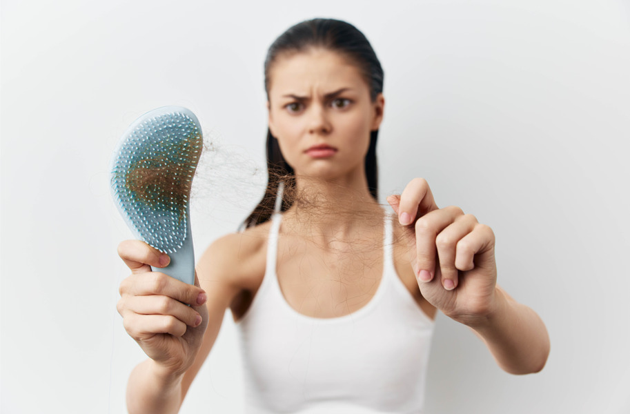 Mulher com escova na mão com queda de cabelo feminino.