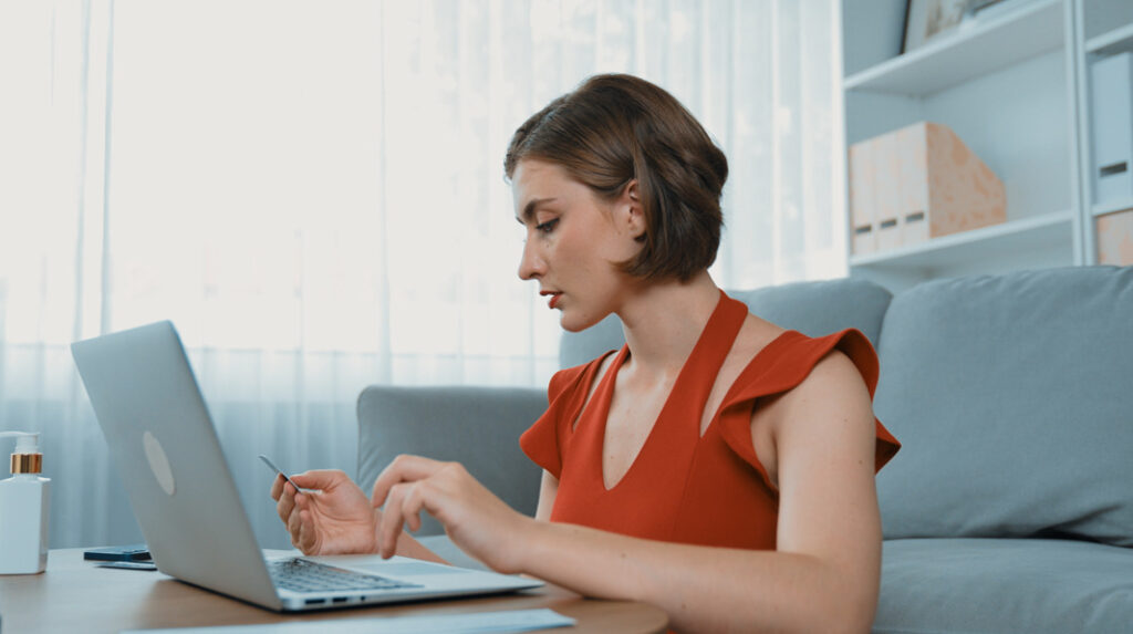 Tricologia estética e clínica: mlher estudando on-line pelo laptop na sala.