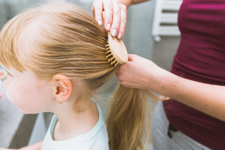 Queda de cabelo em crianças: mãe fazendo penteado na filha.